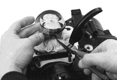 Place a clean rag over the cylinder base to prevent the piston pin circlips from dropping into the crankcase.