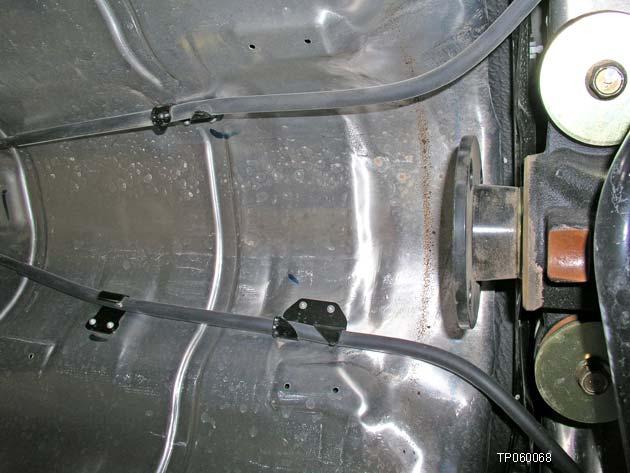 Remove the nuts that hold the parking brake cable brackets to the rear suspension