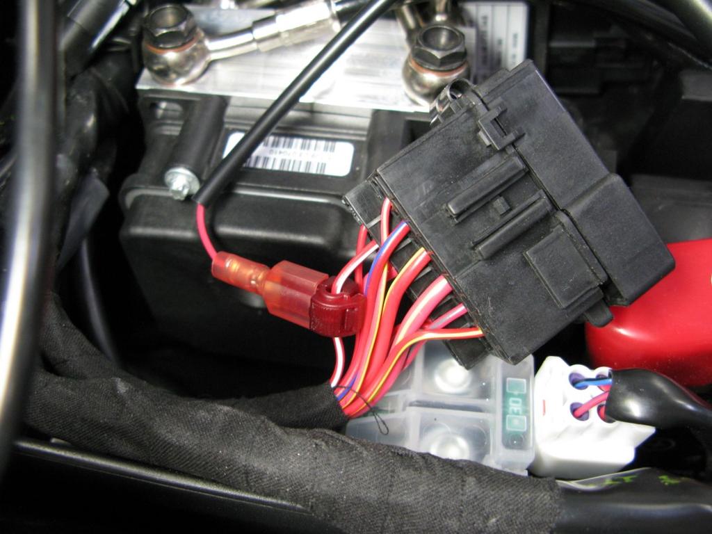 2. Under the rider seat, locate the fuse box (the small black box) to gain access to the red/white wire.