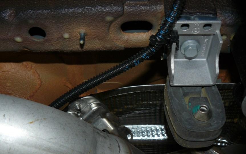 With the entire system supported, loosen and remove the bolts that secure the hangers on either side of the muffler.