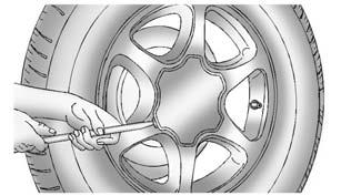 Once the retainer is separated from the guide pin, tilt the retainer and pull it through the center of the wheel along with the cable and latch. 8. Put the spare tire near the flat tire.