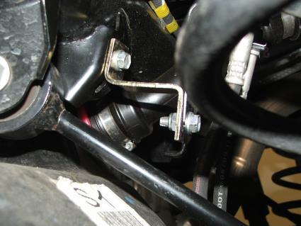 Install the Revtek rear driver side brake line bracket that has two 90 degree bends in it, to the frame using the factory bolt in the stock location and re-attach the Toyota rear brake line bracket