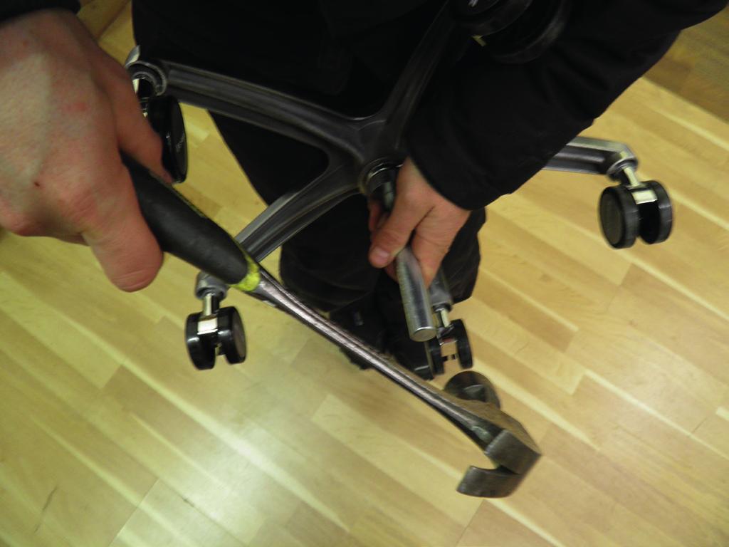 Next place the gas spring upside down between your thighs and lightly apply pressure to it. The caster frame should rest against your thighs. Place the disassembling tool no.