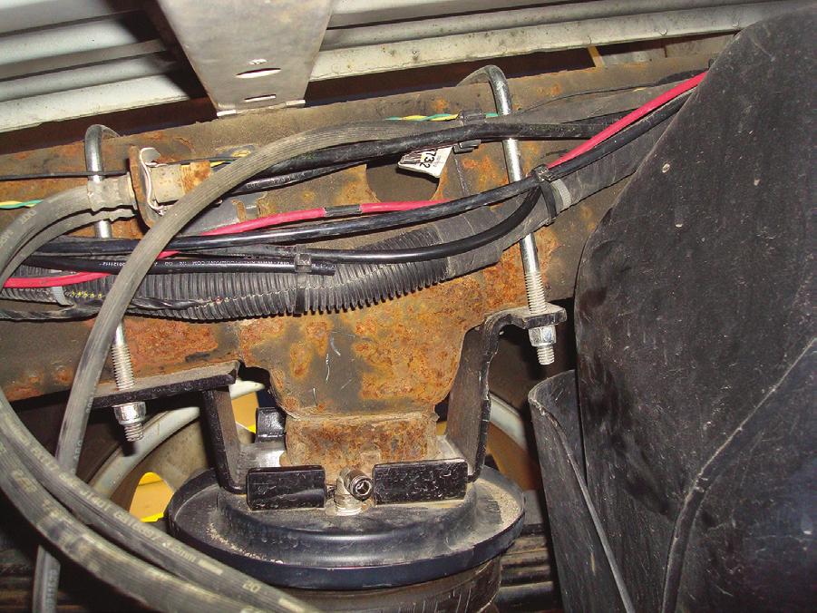 It may be necessary to raise the axle at this point for the upper bracket to reach the frame. H Insert the U-bolts between the frame and brake line harness as shown.