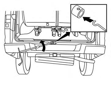 Pass the J-shaped end of the jack rod through the opening and direct it toward the spare tire winch, located directly above the spare tire.