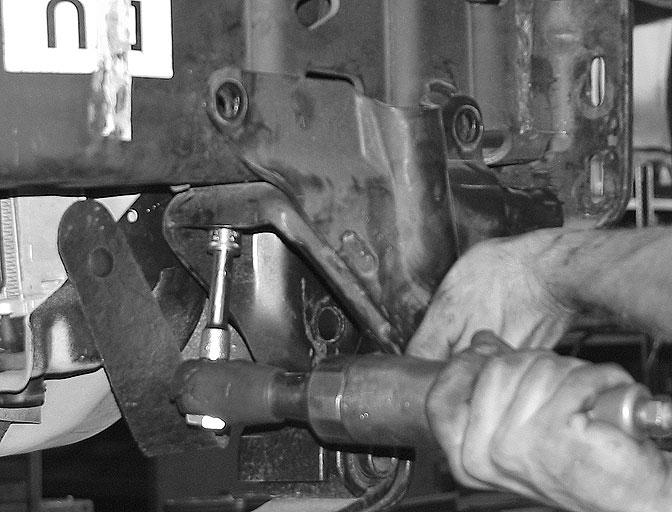 With the floor jacks supporting the axle, remove the front bushing bolts followed by the rear bolts that connect the top of the shackles to the frame, separating the shackles from the frame.