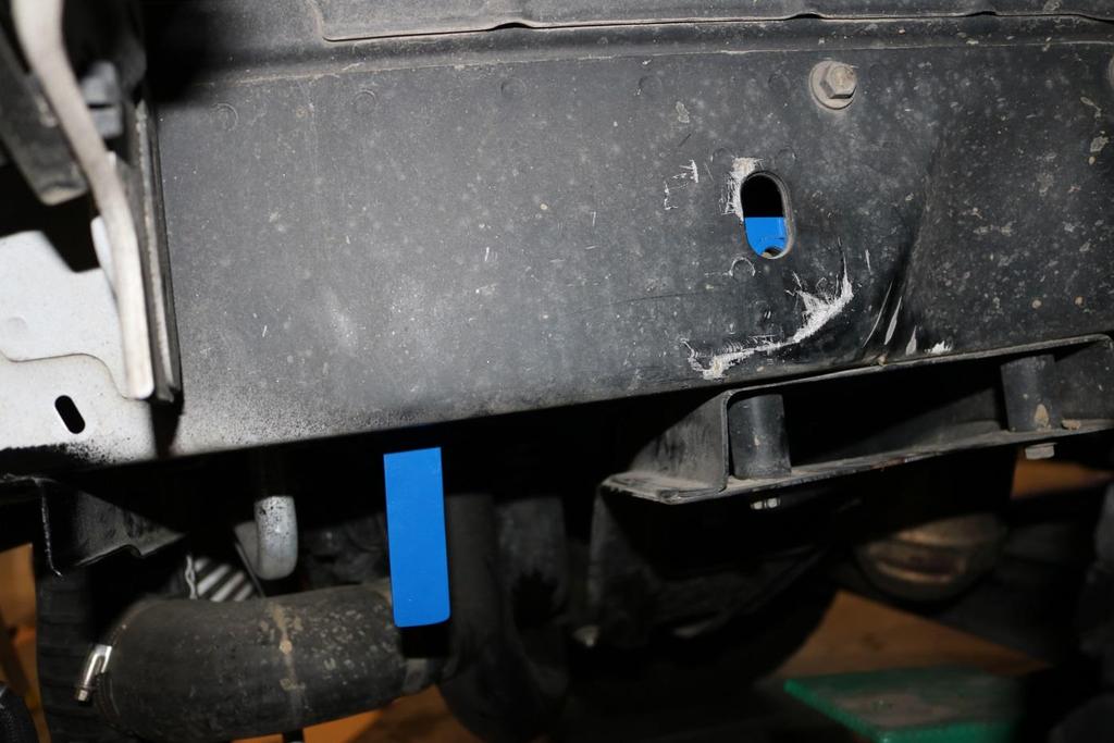 Install the nut tab in the slotted hole in the bottom of the chassis between the engine cross member and the