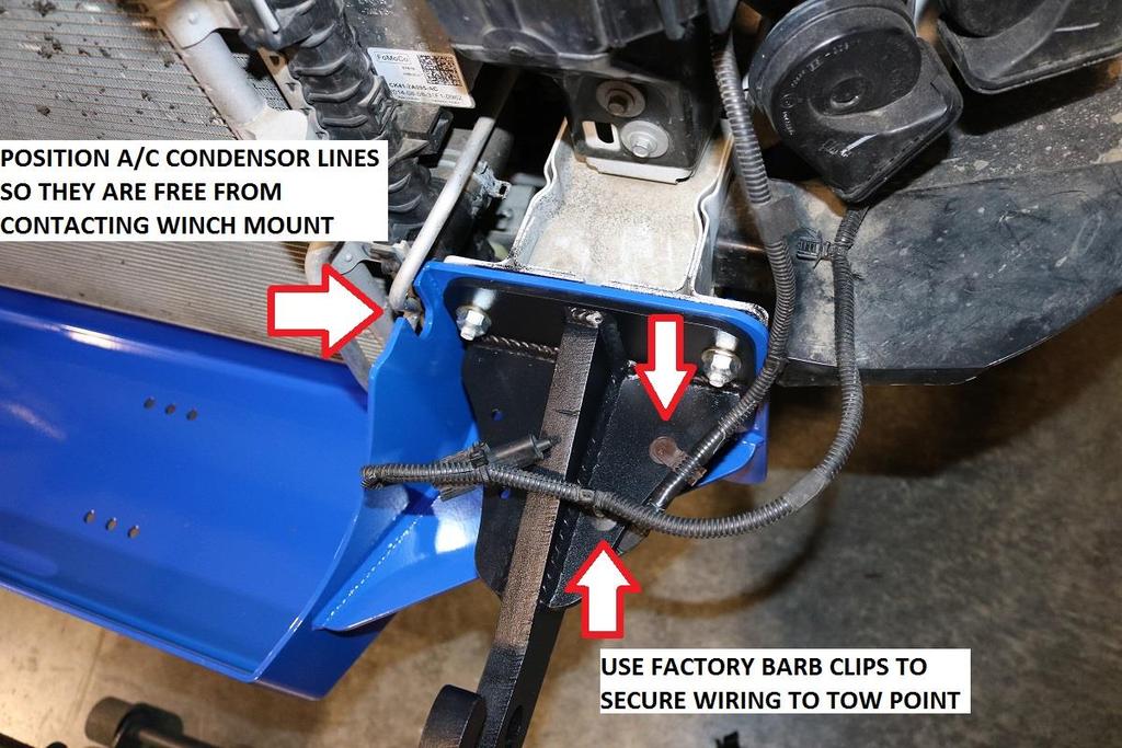 45) If front tow points are utilized, secure wiring to them using the factory barb clips in the holes of the tow point. See image below for reference.