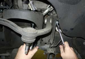 Loosen but do not remove the upper and lower control arm bolts. Remove the upper ball joint from the knuckle.