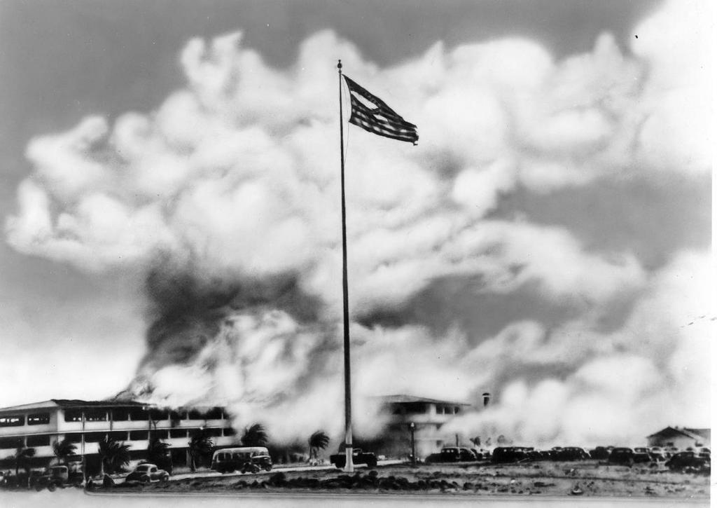 This iconic photo shows Hickam's brand-new barracks in flames after the Japanese attack. The truck at the base of the flag pole belongs to Herb s company, members of which were fixing a damaged cable.