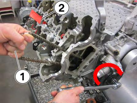 Hold the timing chain in one hand (1) and rotate the engine slowly in the clockwise direction (see arrow) while keeping the tension on the chain with one hand (1).