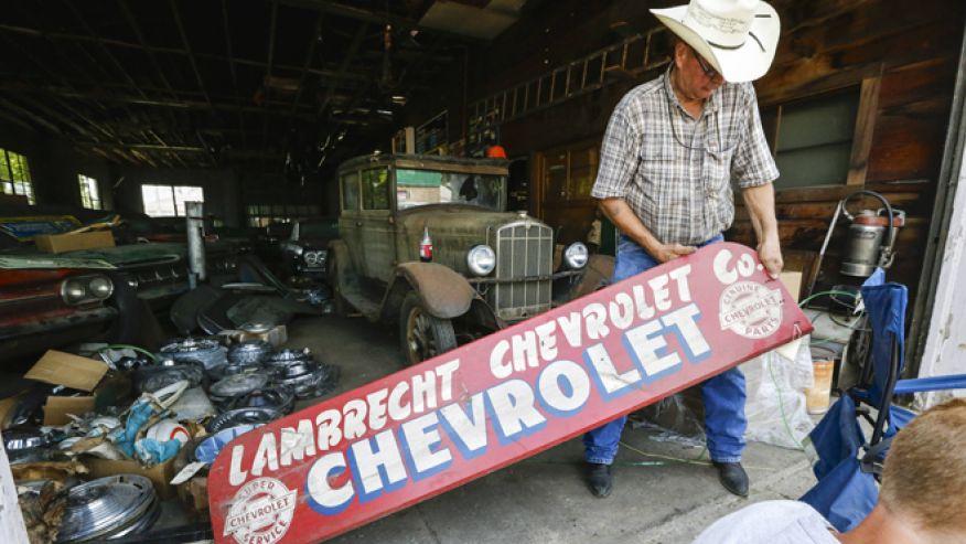 In this Aug. 12, 2013 photo, Art Nordstrom holds a sign at the former Lambrecht Chevrolet car dealership in Pierce, Neb. In Se