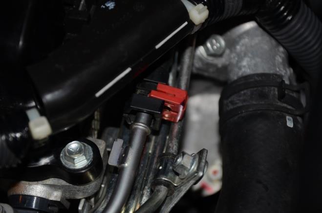 Locate the fuel feed line near the OEM boost control solenoid. The fuel feed line is a rubber hose with a red clip that attaches to the hard fuel line.