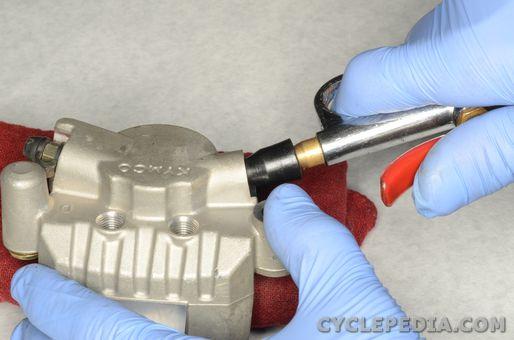 Place a thick rag over caliper piston and use compressed air to move the piston out.