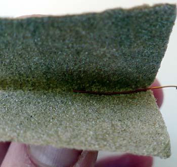 Figure 10. A "sandpaper sandwich" is used to remove the insulation from the ends of the magnet wire. Tutorial video for stripping insulation from hookup wire. https://www.youtube.com/watch?
