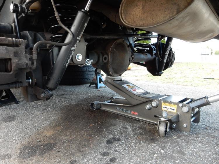 Using the floor jack, carefully lower the front axle far enough to remove