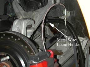 Find the metal loom holder and the sheet metal screw with the 10 mm head (part #24). Place the metal loom holder on the red cable oriented so that the cable is being held inboard and tighten screw.