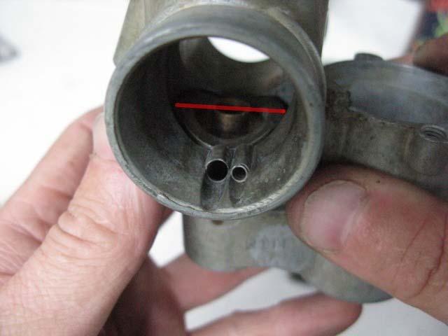 This is the idle mixture hole visible at the bottom of the carb bore on the engine side of the throttle slide.