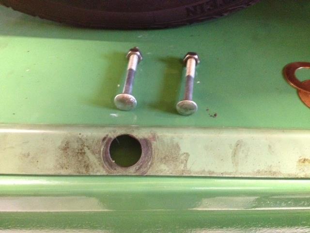 The half shaft pokes through the hole and the coach bolts sit in the holes in the end of the axle case where the back plate bolts to with the heads up against