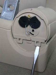 To remove the rear cup holder (if applicable), push down the two retaining tabs indicated by the arrows in the