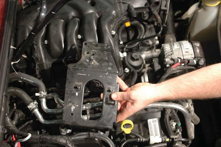 Lift up on the heater lines, slide the bracket down toward the exhaust manifold