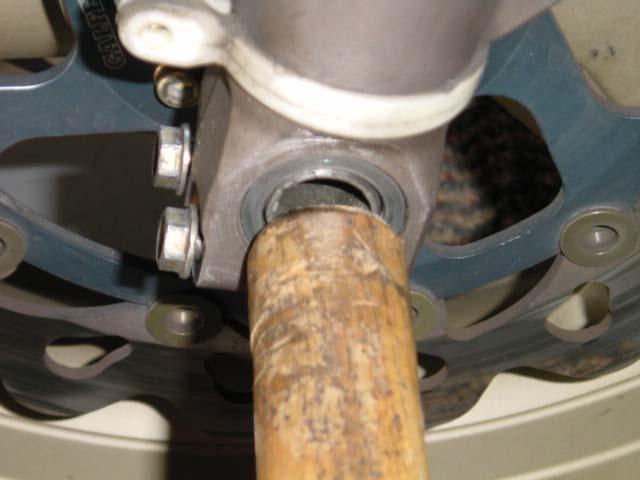 5. Using a soft material- such as a plastic or wooden dowel, push out the axle while supporting the weight of the front wheel.