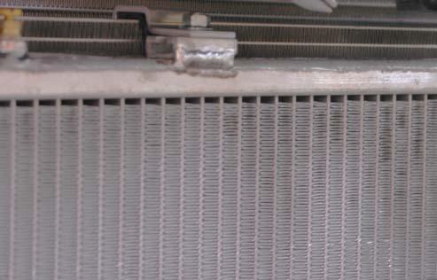 Carefully slide the heat exchanger up in front of the AC condenser and hook the upper mounting brackets over