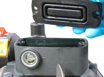 Remove the two master cylinder cover screws with a #2 Phillips head screwdriver.