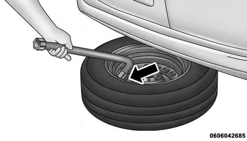 3. Rotate the wheel wrench handle counterclockwise until the spare tire is on the ground with enough cable slack to allow you to pull it out from under the vehicle.