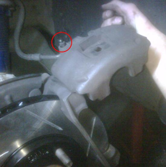 Brake caliper. The bleeder valve is circled in red. 11. Loosen bleeder valve nut with the 3/8 wrench 1/4 turn.