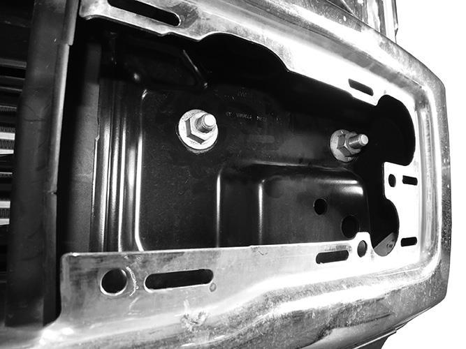 From behind bumper, release metal clips attaching plastic