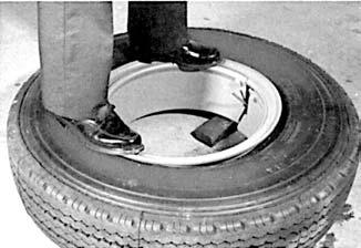 Spread the rim by placing a block under the left side of the split (when facing split). Align the valve with the rim valve slot and work the tire onto the rim.