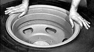 Place the flange over the rim and then stand on the flange to push it below the rim gutter Work the first tire bead down into the well of the rim next to the