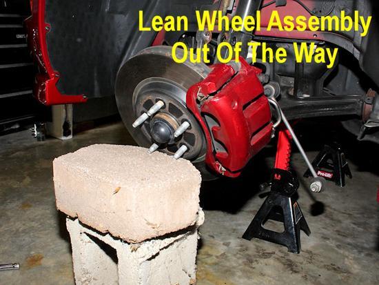 9. Once the lower strut bolts are removed, the suspension arm will fall free. Support it with something similar to a jack stand or a cinder block.