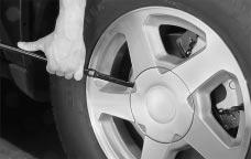 2. Turn the wheel wrench counterclockwise to lower the spare tire. Keep turning the wheel wrench until the spare tire can be pulled out from under the vehicle.