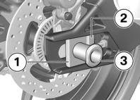 Raise the rear wheel and install the quick-release axle 3 through the shim in the brakecaliper support and the rear wheel.