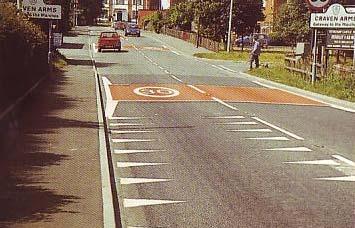 This had speed limit roundel markings on both lanes of the carriageway, placed on a red background strip. Between the repeat roundel markings there was centre hatching in-filled with a red surface.