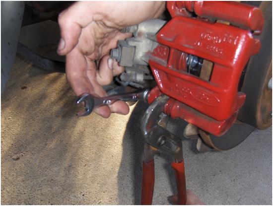 Leaving the top bolt in will make it easier to loosen the bottom bolt without the caliper moving on you. 5.