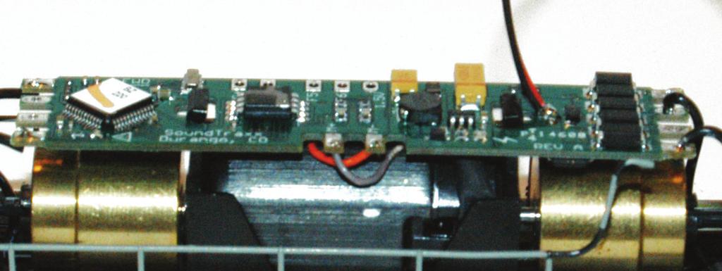 Use the same two tabs to hold the Tsunami decoder in place that were used to hold the factory light board in place. Then solder the track pick-up wires to the decoder.