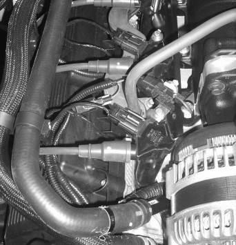 Route the wires behind the fuel rail and underneath the heater hoses. Torque the bolt to 10 Nm.