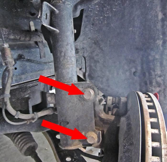 Remove the (2) strut-to-spindle bolts using an 18mm socket (use an impact wrench if available). Note: Set aside the (2) strut-to-spindle cam nuts that become disengaged when bolts are removed.