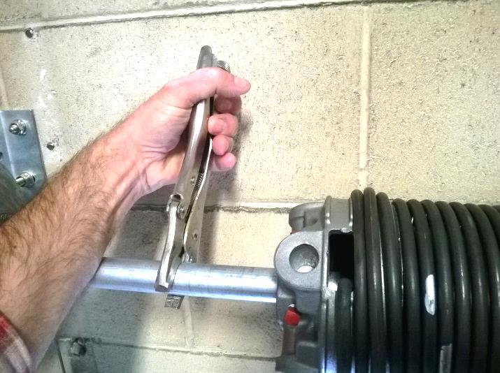 Figure 77 5. Vise grip the shaft as shown to keep the lift cable tight on the drum. The top of the vise grip should be tight against the door wall.