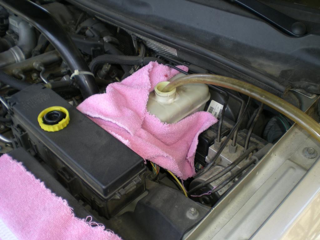 Remove the cap from your brake reservoir. If it is very full, remove a little fluid. Place rags all around to catch any fluid that spills.