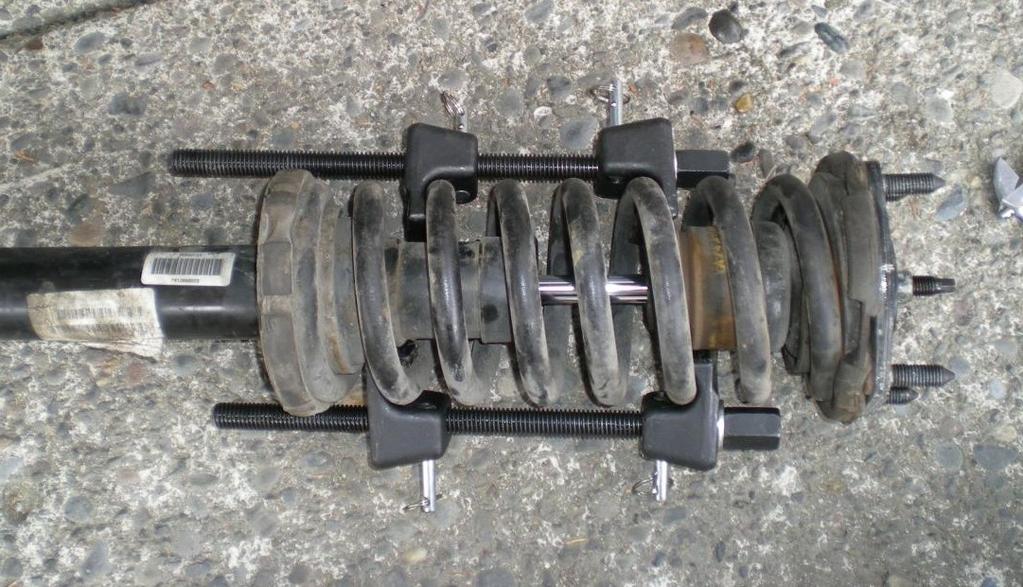 Put your spring compressors onto the springs and tighten them down to compress the spring. Compress it enough so that you can remove the nut at the end of the shock.