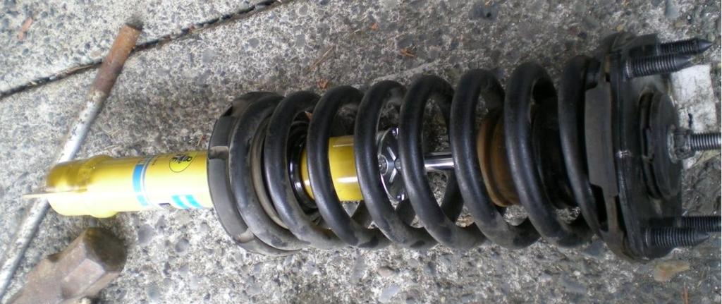 Place the new shock into the spring. Line up the mark with the flange. Pay close attention to the slant of the lower flange and note how the rubber bumper engages the spring.