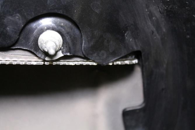 With the factory ducting in place, put a pick through one of the holes near a nut that secures it. Use the pick to push the insert towards the front of the hood.