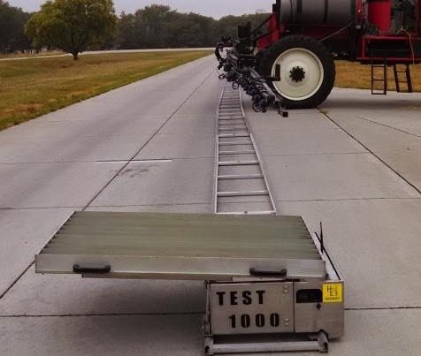 Figure 5. Herbst Sprayertest 1 on tracks placed below Apache AS12 sprayer, with the spray pattern collection device installed on the end of the tracks (foreground of picture).