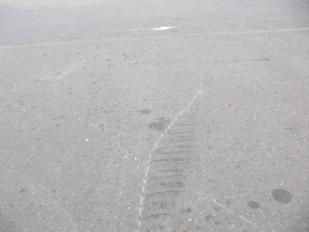 Close-up view of the short tire mark with striations and the thin scratch in the pavement.