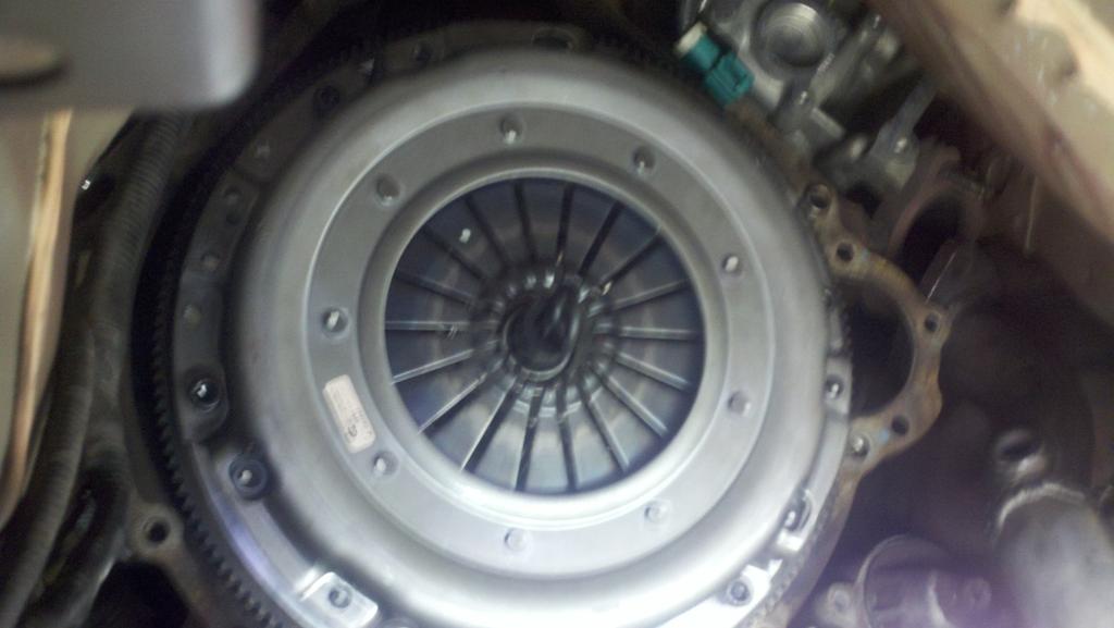 18. Install Clutch kit: Place disk on flywheel, making sure the sides are as labeled. Use the alignment tool to keep the disk held in place while installing the pressure plate.