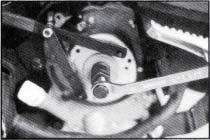 Use universal wrench to hold flywheel, and rotate